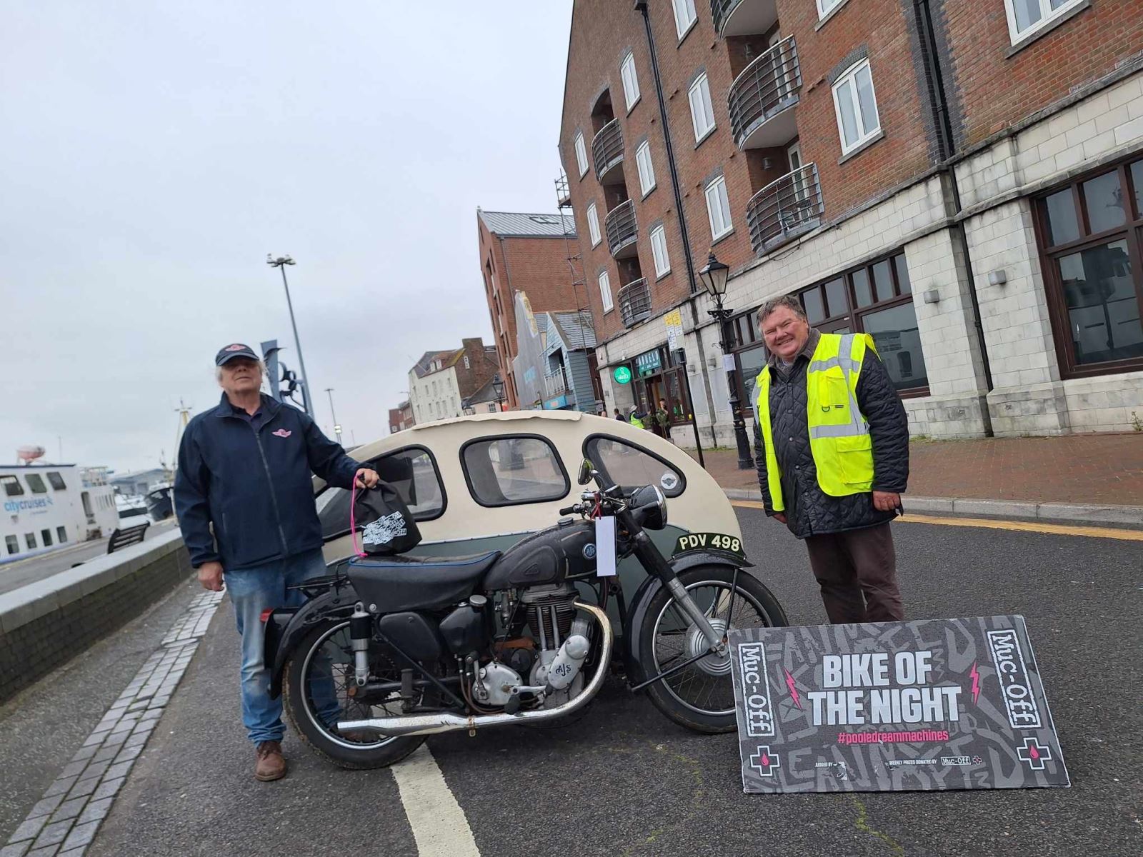 Bike night winner standing next to a judge with his motorbike 